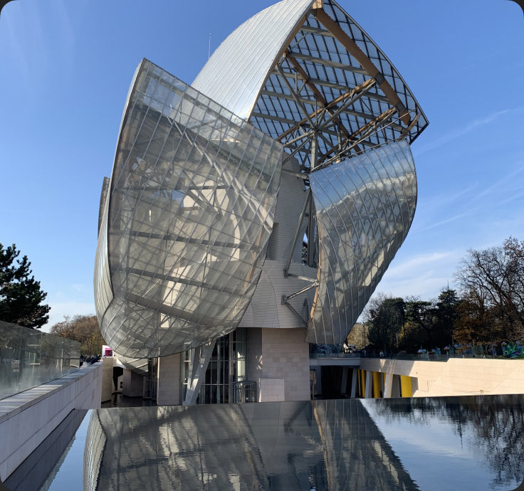 The glass sails of the Fondation Louis Vuitton, mirrored in water — Paris, France