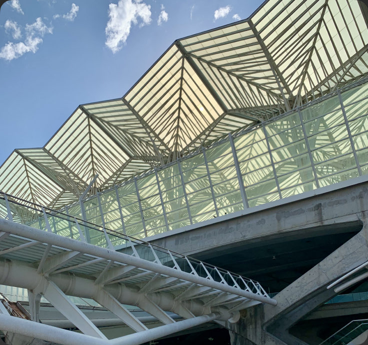 A folded glass-and-steel roof seen from below — Gare do Oriente, Lisbon, Portugal